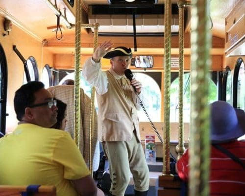 Guide in colonial clothing giving tour inside Liberty Ride trolley.